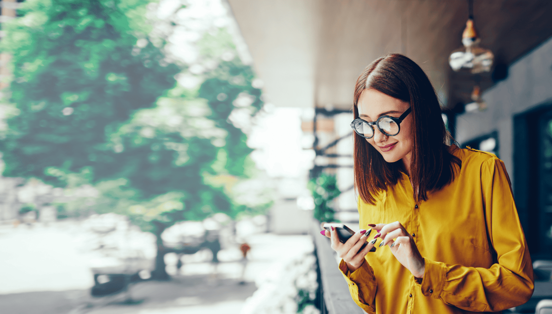 Woman standing by the window looking at her phone.