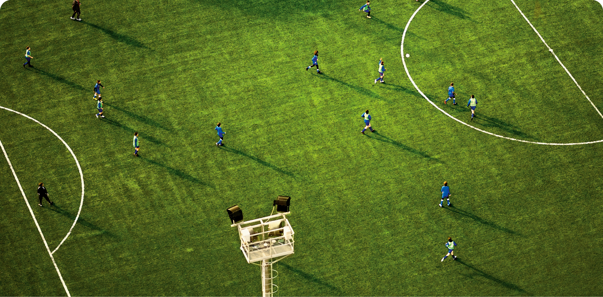 Gaming hero image of a longshot image of blue and green players playing football.