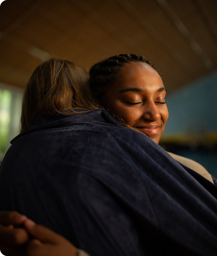 A picture of two brown haired women embracing and smiling