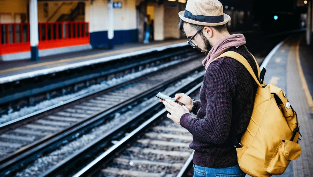 Man with hat, glasses and bag waiting in platform