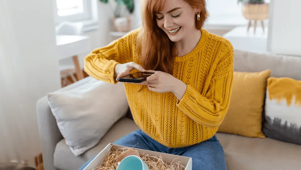 Woman taking a picture with smartphone to a cup in a box