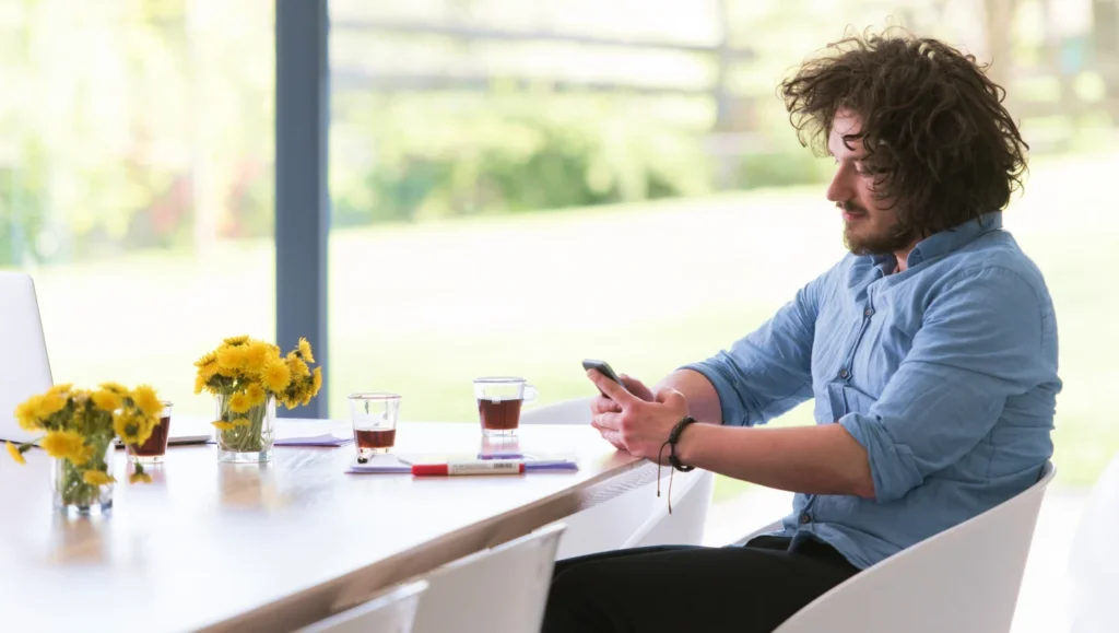 Man with a smartphone taking a cup of tea