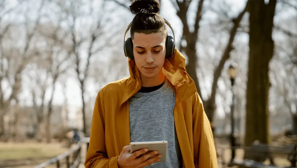 Young man with headphones at the park watching his tablet