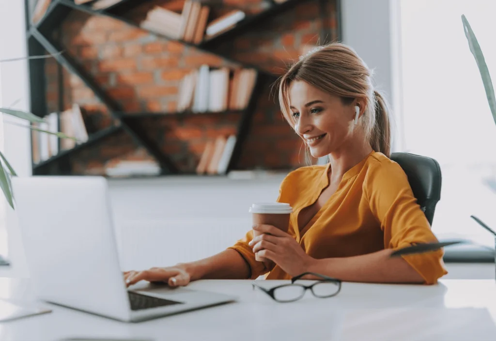 Woman with coffee and laptop smiling