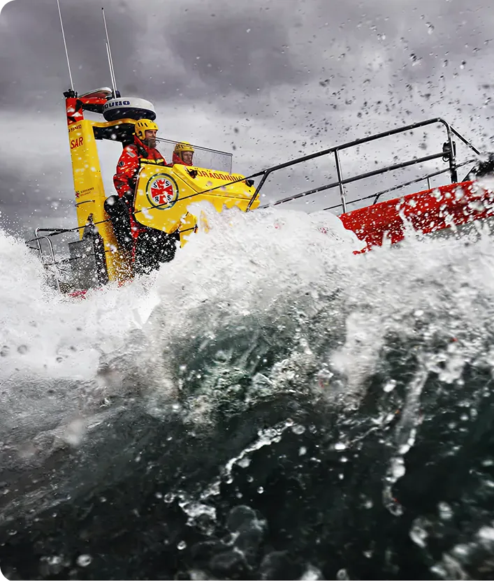 A sea rescue boat riding through a storm, with two sailors onboard